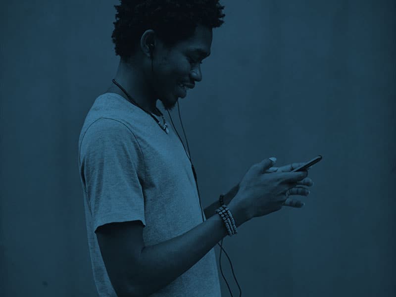 A young man is listening to music on his cell phone.